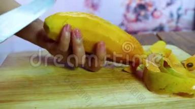 年轻女人打扫和切芒果。 女孩剥芒果，拿在手里，用刀切下。 剥熟芒果，熟芒果和